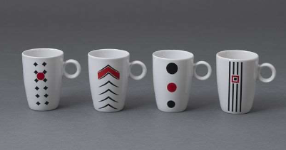 Vier kleine Tassen aus Kamino Porzellan stehen nebeneinander. Sie sind weiß und mit schwarz-roten Mustern dekoriert. Sie entstanden im Jahr 2010.