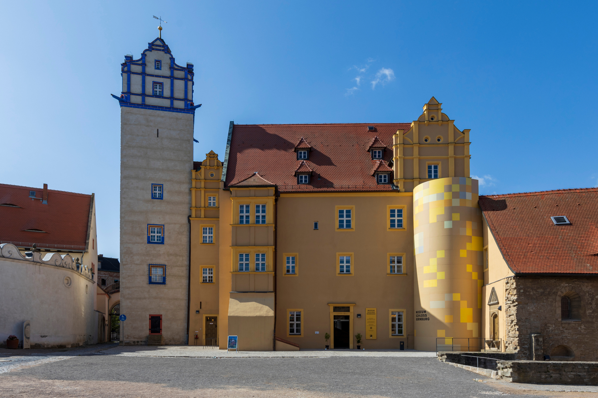 Fassade des Museums Schloss Bernburg mit dem Blauen Turm neben dem teilweise gelben Hauptgebäude.