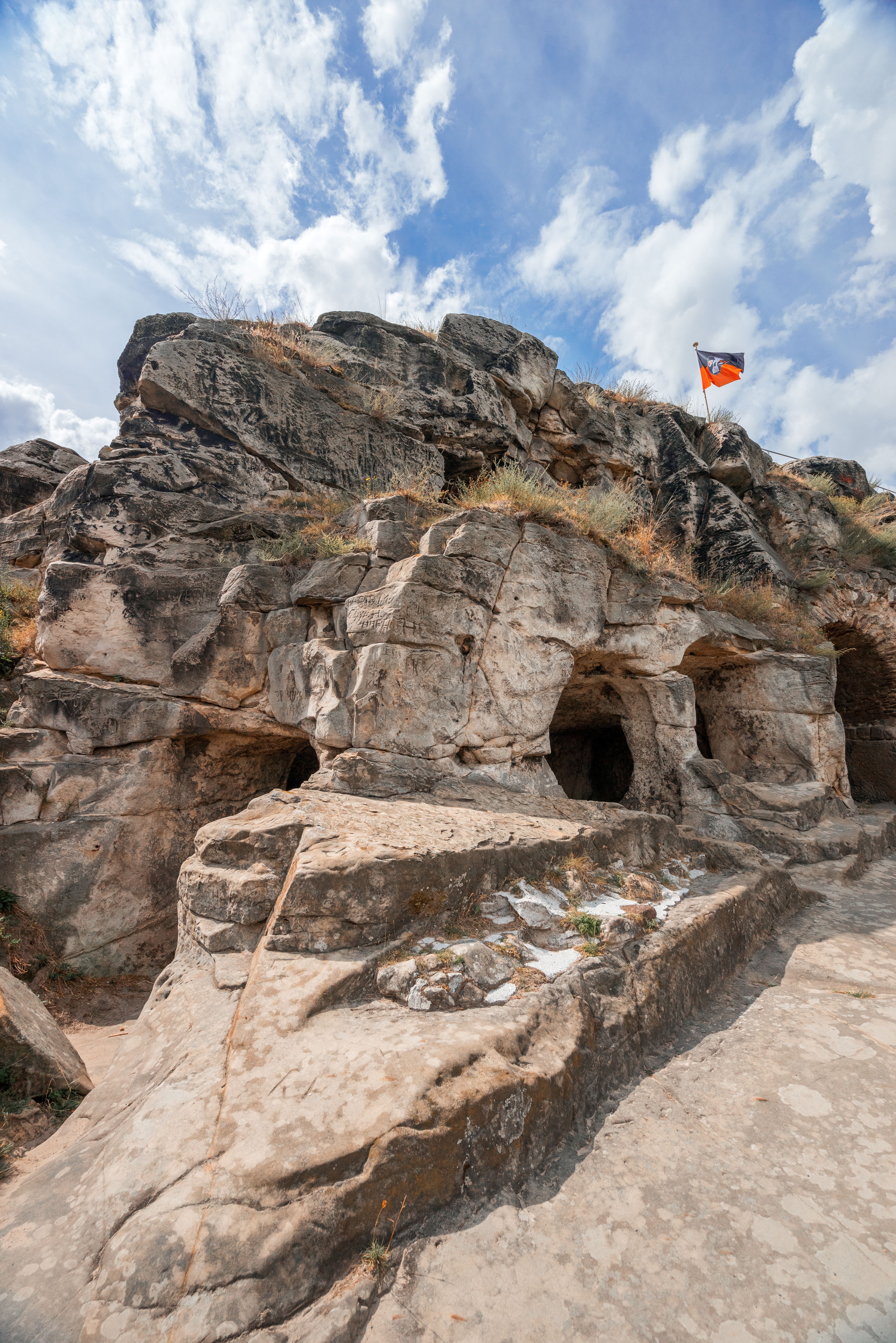 Die Kernburg der Festung Regenstein. Felsen und große Steine dienen als Wohnraum. Ein Flagge steht auf dem Felsen.