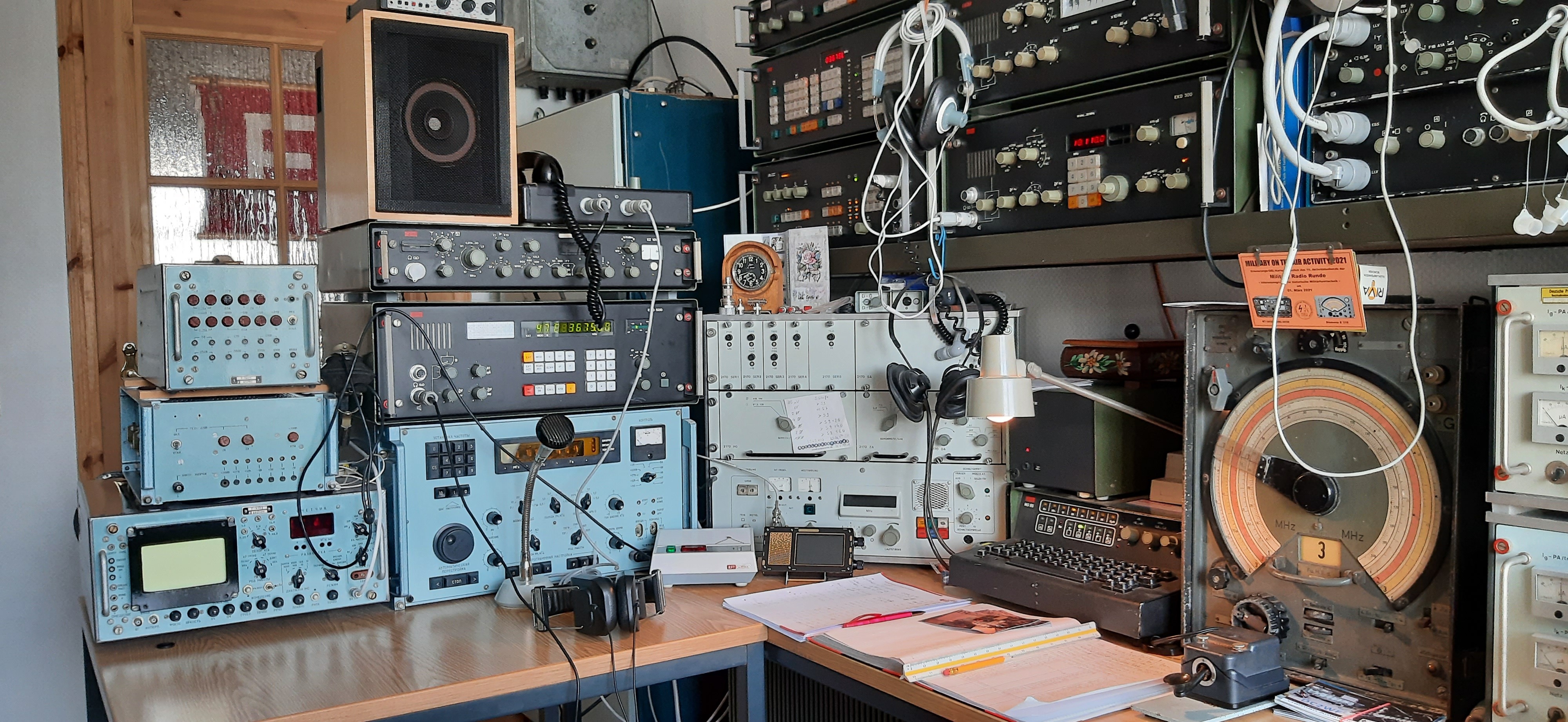 Auf zwei Tischen wurden technische Apparate als Funkstation aufgebaut. Darunter befinden sich mehrere Kopfhörer, Lautsprecher und ein Mikrofon.