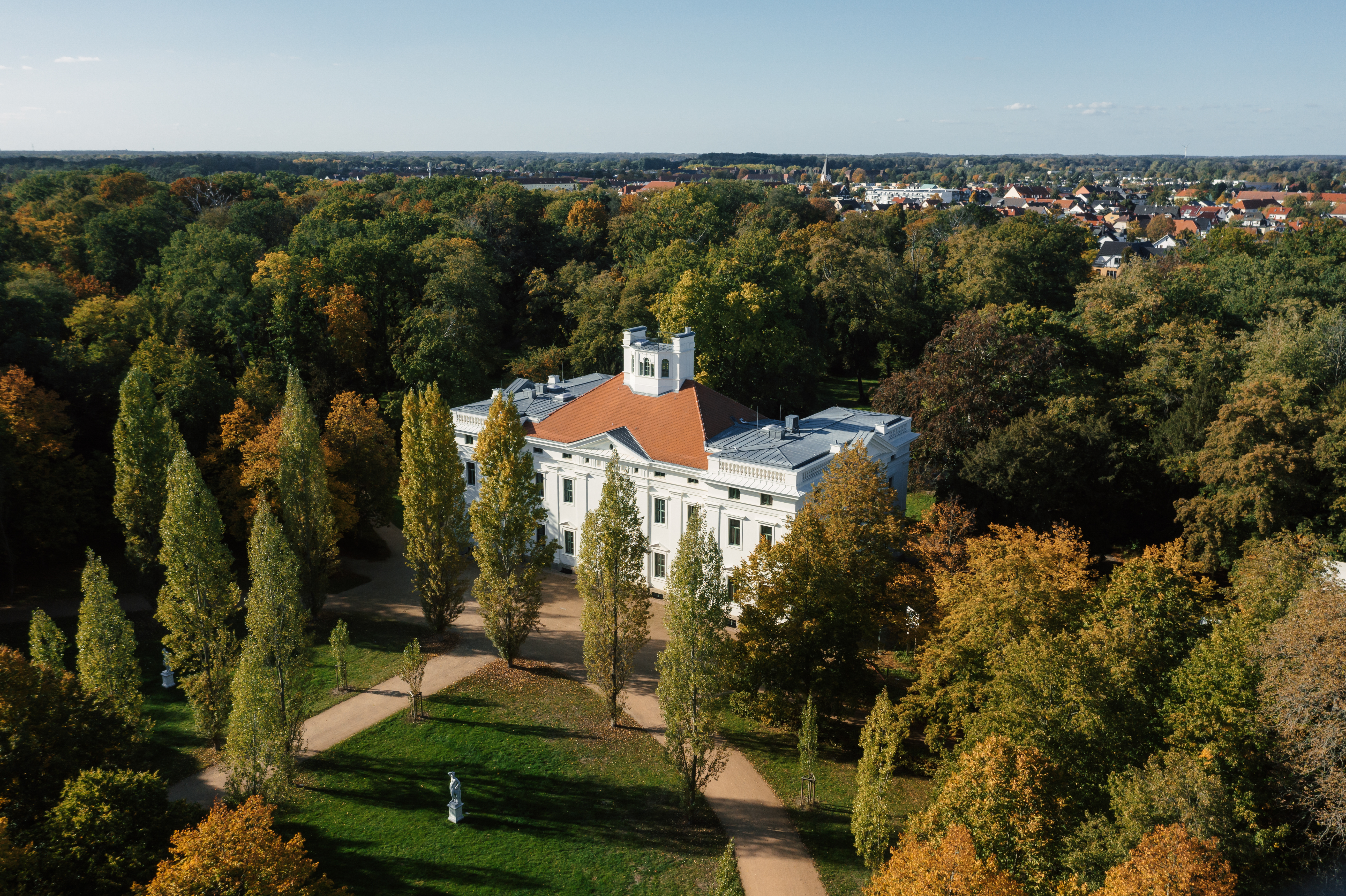 Das weiße Schloss Georgium aus der Vogelperspektive in einem grünen Park.