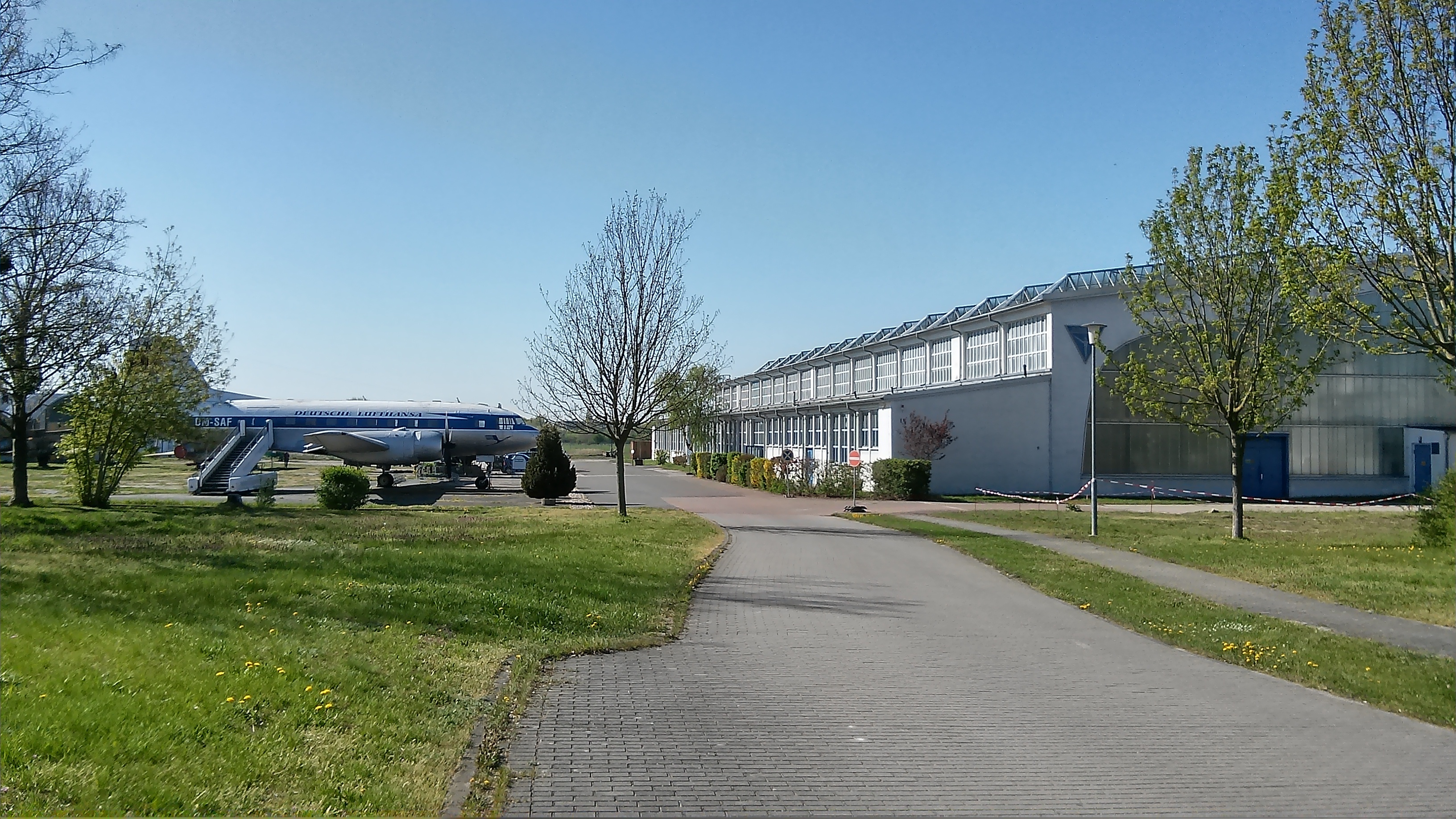Auf dem Weg zur Museumshalle steht bereits ein weiß-blaues Flugzeug auf der Wiese gegenüber.