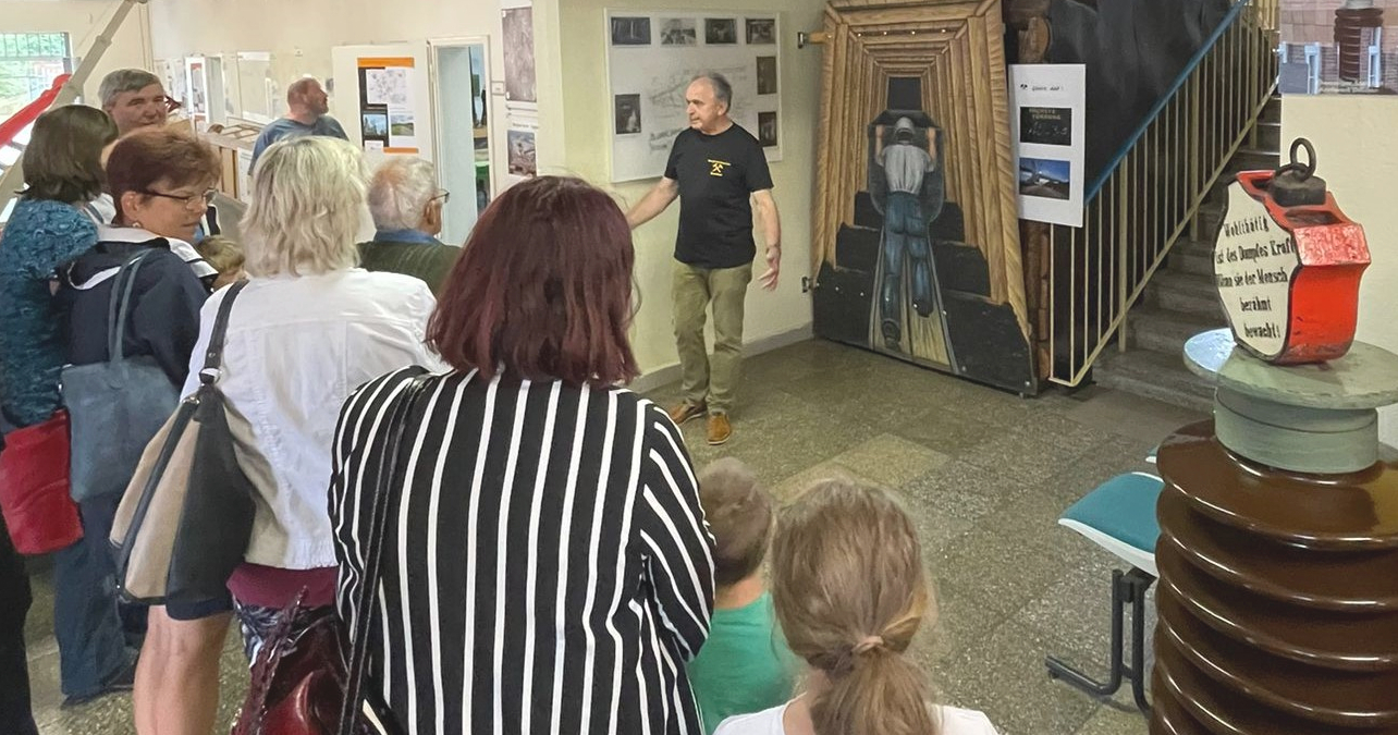 Führung durch das Bergbaumuseum Deuben. Eine Personengruppe steht um einen Museumsmitarbeiter bei einer Führung.