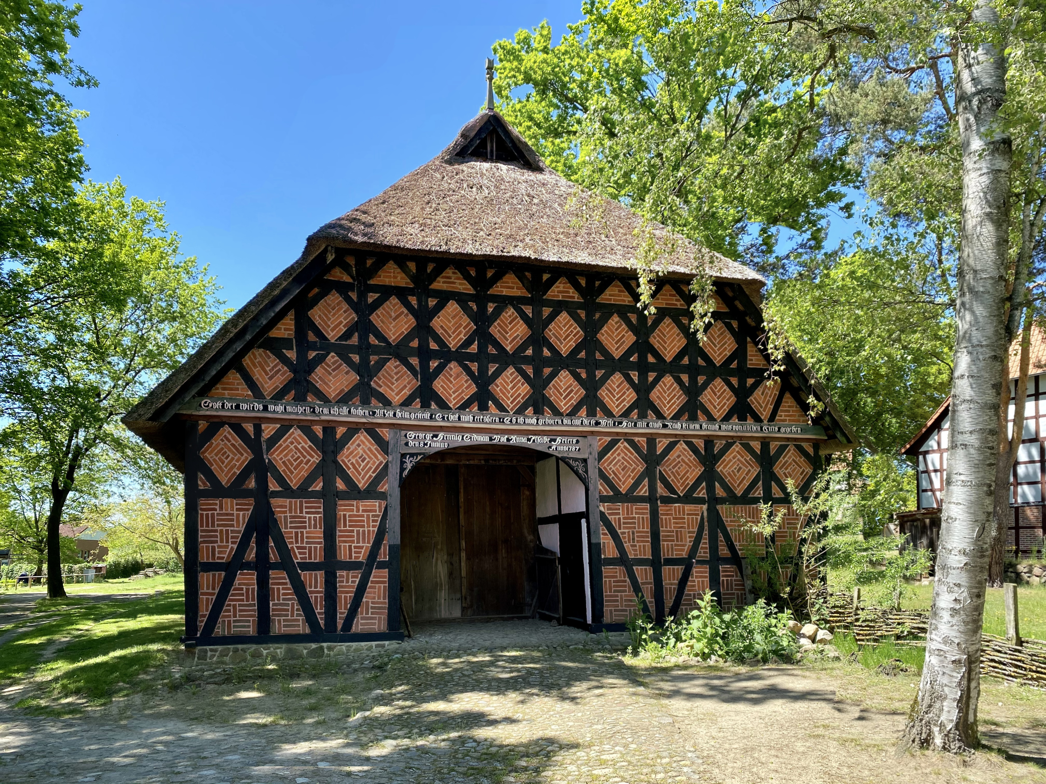 Freilichtmuseum Diesdorf Winkelstedter Hallenhaus. Ein kleines Haus aus Backstein und dunklem Fachwerk mit einem Reetdach.