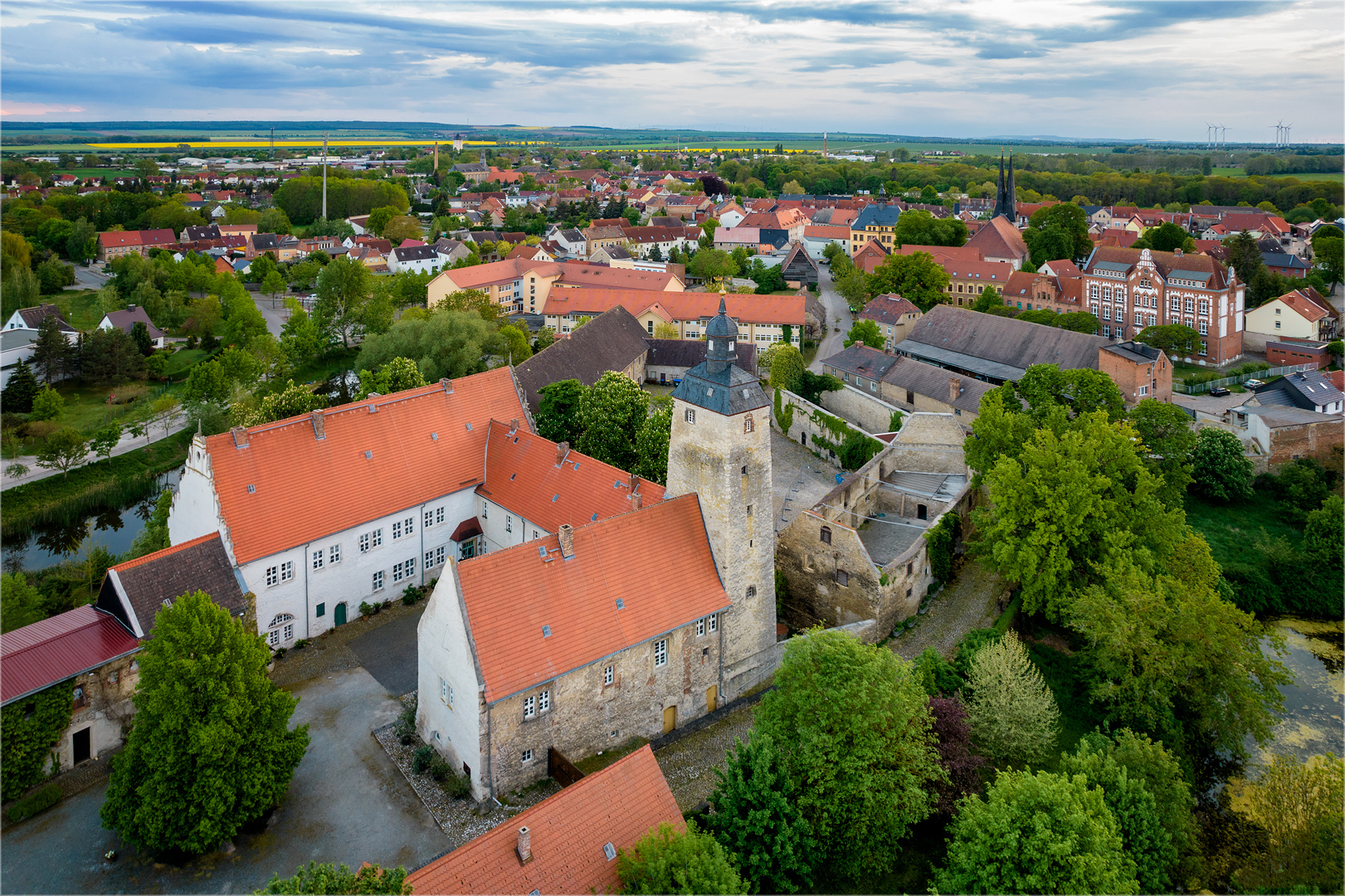 Die Wasserburg Egeln von oben. Mehrere Häuser ohne Dach umgeben die Burg, die aus einem Bergfried und einer dreiseitigen Anlage besteht.