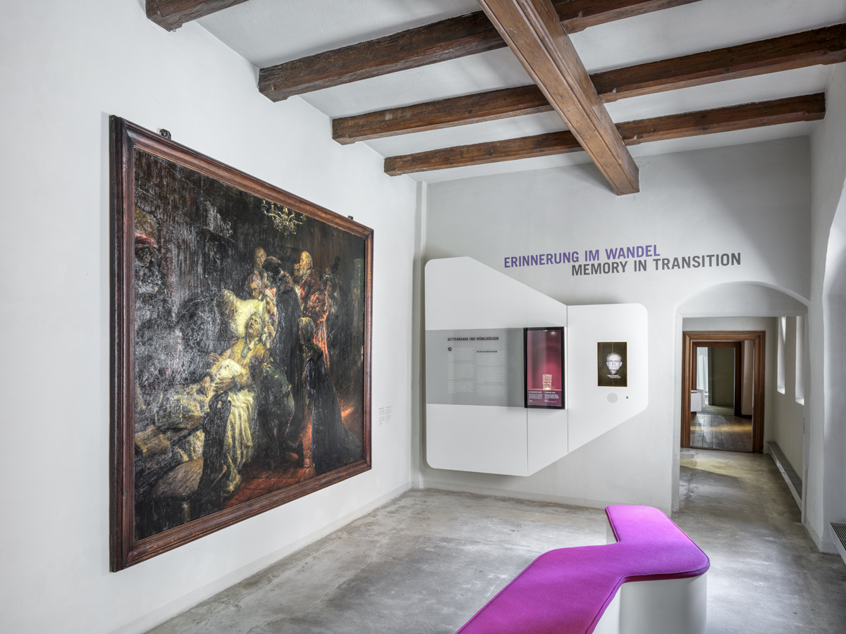 Luthers Sterbehaus. In einem Ausstellungsraum hängt das großformatige Sterbebild Luthers. An einer Wand daneben steht in violetter Schrift: "Erinnerung im Wandel / Memory in Transition." Eine Bank in der gleichen Farbe steht vor dem Bild.