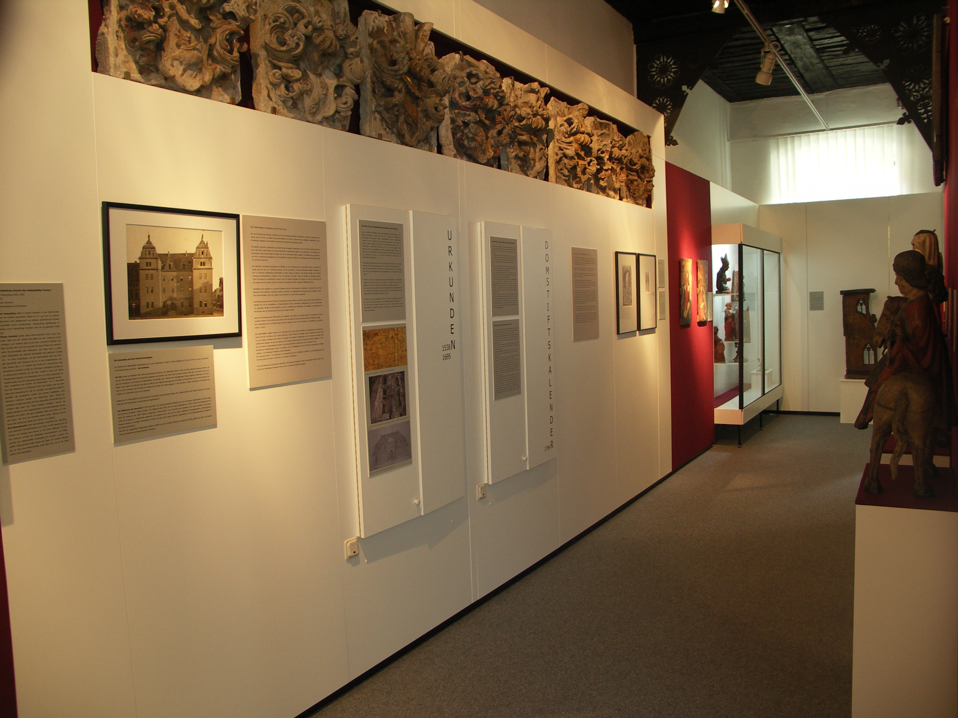 Ein besonderer Ausstellungsabschnitt beschäftigt sich mit dem Wirken des mächtigen Domkapitels und zeigt phantastische Werke sakraler Kunst.
An einer weißen Wand wurde eine Reihe von Wappen aus Stein angebracht, darunter hängen Tafeln mit Texten und Bildern. Gegenüber stehen zwei Skulpturen, eine davon reitet auf einem Pferd.