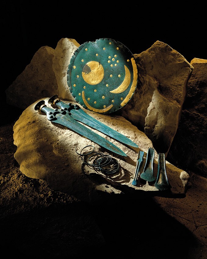 Auf zwei großen Steinen wurde der Befund Hort Nebra rekonstruiert. Die Himmelsscheibe von Nebra (eine kreisförmige Bronzeplatte mit Applikationen aus Gold, welche den Himmel darstellen) steht hinter zwei Bronzeschwertern und Beifunden, wie zwei Randleistenbeilen, einem Meißel und Bruchstücken spiralförmiger Armreifen.