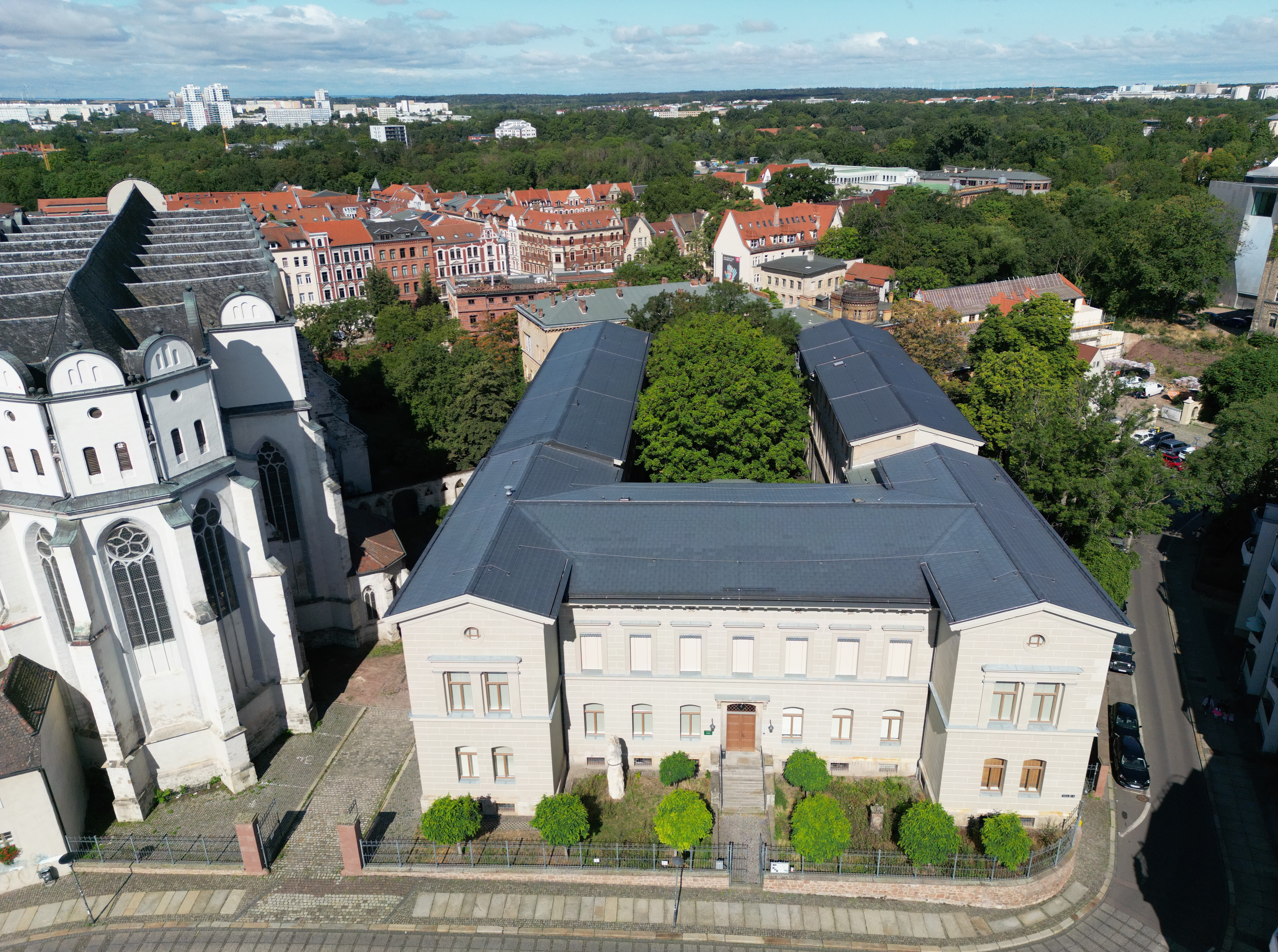 Außenansicht des Hauptgebäudes des Zentralmagazins Naturwissenschaftlicher Sammlungen der Martin-Luther-Universität Halle-Wittenberg, zentral am Domplatz in Halle (Saale) gelegen. Im Innenhof des Museums stehen große Bäume. Neben dem Gebäude steht der Hallesche Dom.