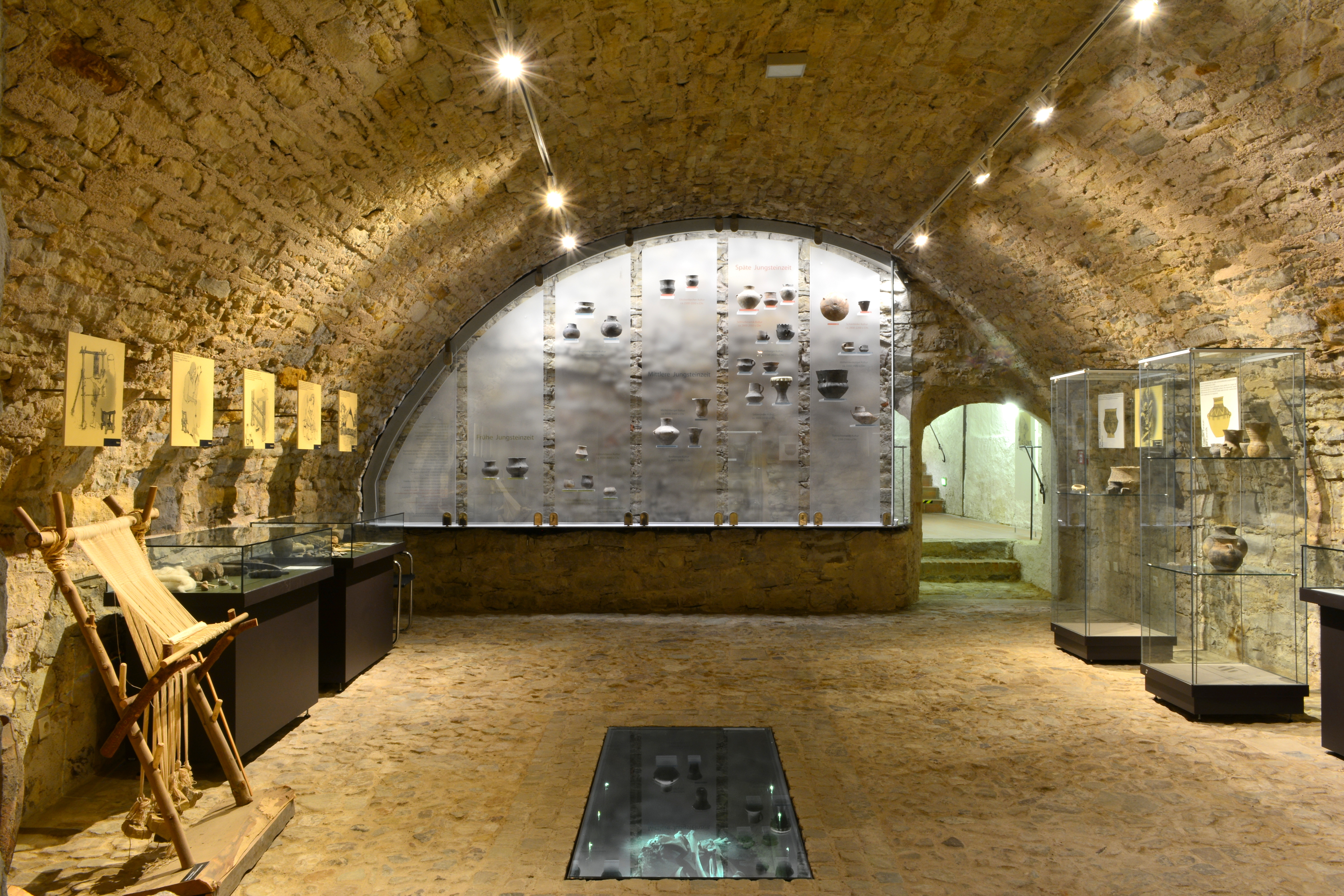 Im Gewölbe werden Funde aus der Jungsteinzeit ausgestellt. Diese werden hinter Vitrinen gezeigt. Im Boden ist eine Glasplatte eingelassen.