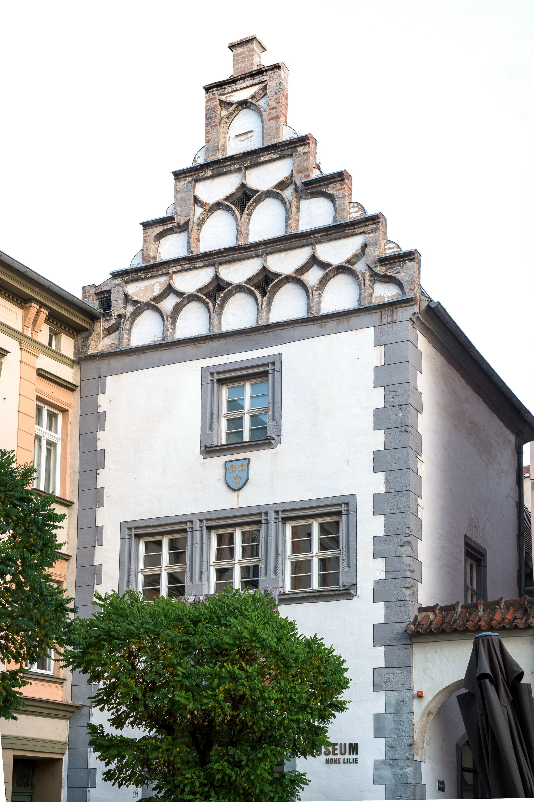 Das Haus zur Hohen Lilie im Stadtmuseum Naumburg. Das weiße Gebäude besitzt einen auffälligen Stufengiebel. Ein kleines blaues Wappen mit drei goldenen Lilien schmückt die Fassade.