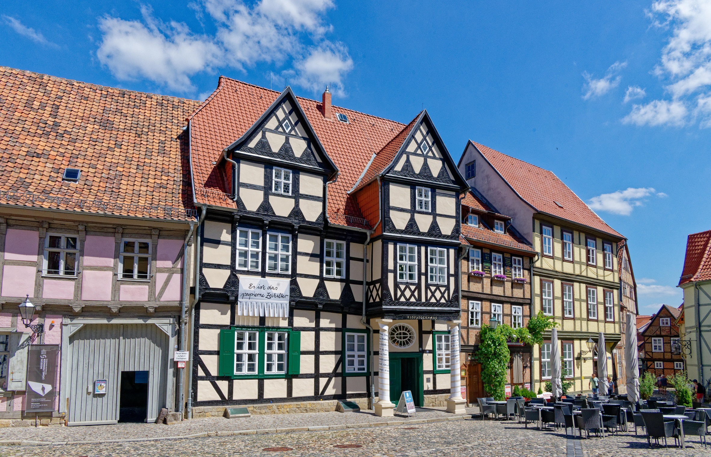 Die Fassade der Klopstockhauses reiht sich zwischen bunte Fachwerkhäuser ein. Das Haus selbst ist gelb mit dunklem Fachwerk und grünen Fensterläden.